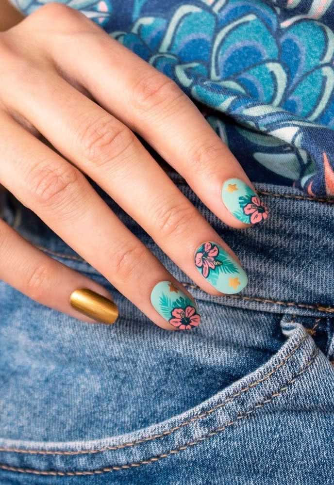 O esmalte azul traz um toque tropical e festivo às unhas decoradas com flores. Para fechar o look, um toque de dourado