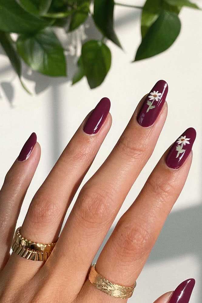Já para um visual mais sofisticado, aposte em unhas decoradas com flores sobre um esmalte vinho