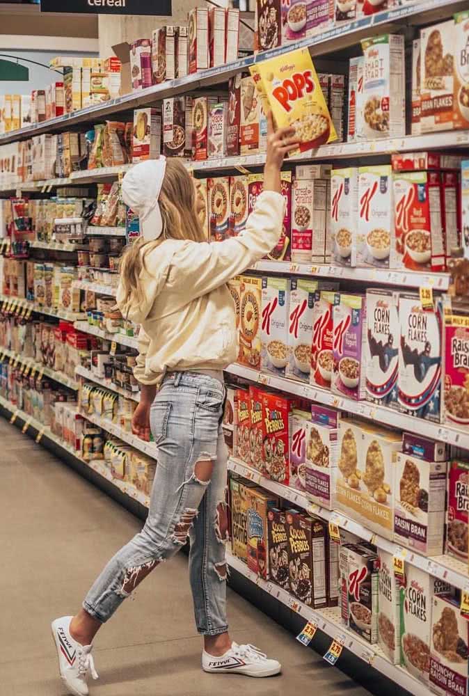 Uma autêntica vsco girl no supermercado com calça jeans destroyed, boné e tênis