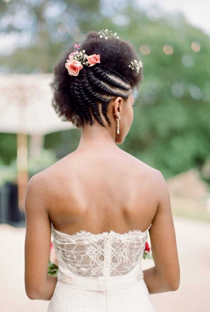 Penteado afro para noiva: tranças na nuca e lateral com o restante solto. Finalize com flores
