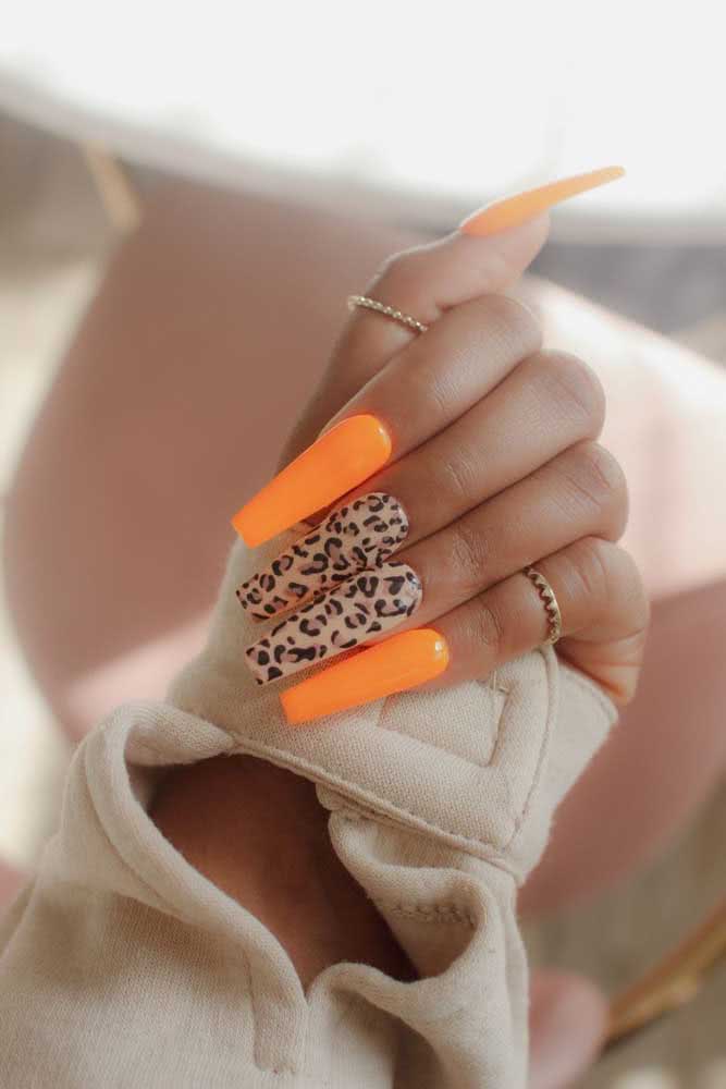 Para arrasar quarteirão: unhas neon laranja stiletto intercaladas pela decoração de oncinha