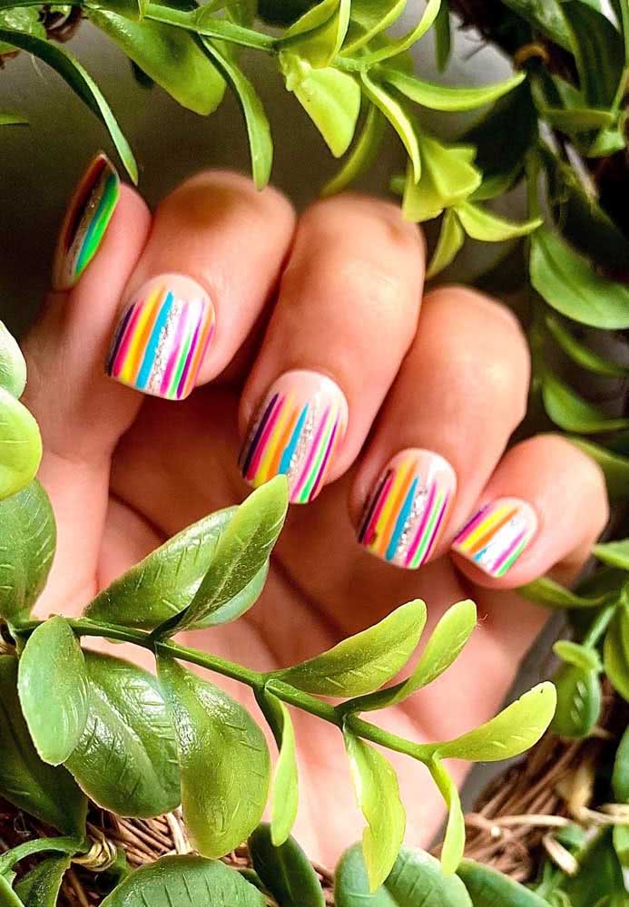 Para se diferenciar um pouco, aposte em unhas listradas neon 