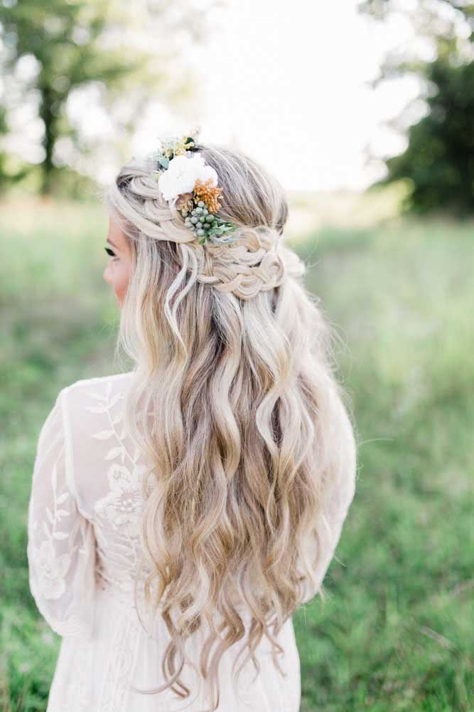 Uma coroa na cabeça feita com não uma, mas várias tranças soltinhas e um adorno floral compõe esse look boho 