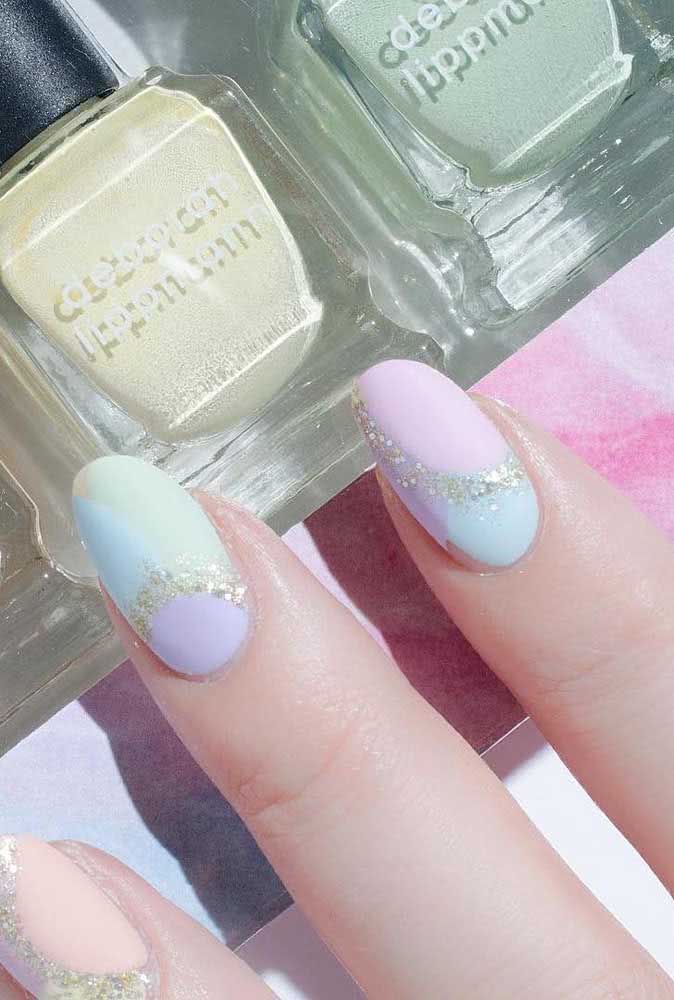 Unhas com glitter seguindo a linha divisória entre os esmaltes tom pastel