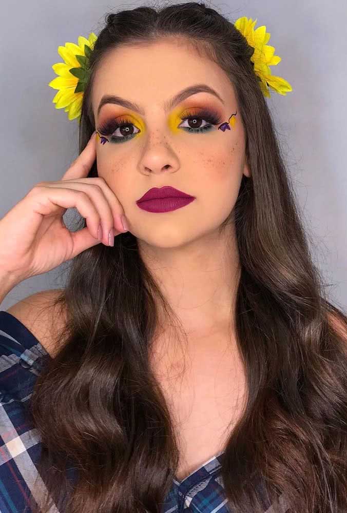 Já nesta make, o destaque vai para a sombra esfumada nos olhos, com as cores dos girassóis, também presentes no penteado