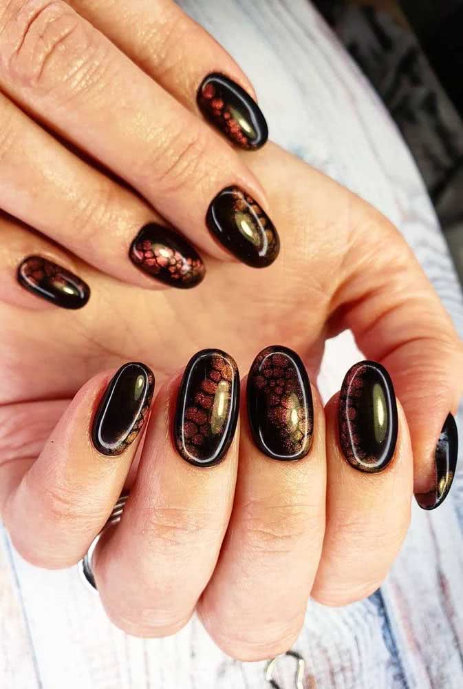 Use esmaltes perolados para criar um efeito craquelado sutil nas suas unhas pretas decoradas