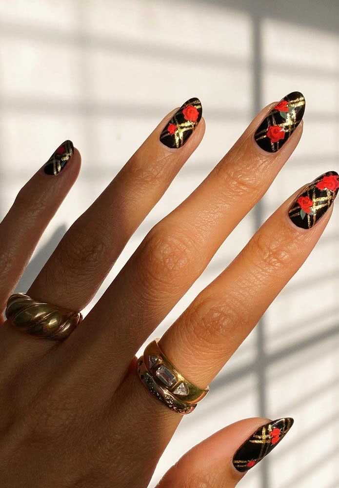 Padrão em dourado e flores vermelhas dão o toque final nessas unhas pretas decoradas