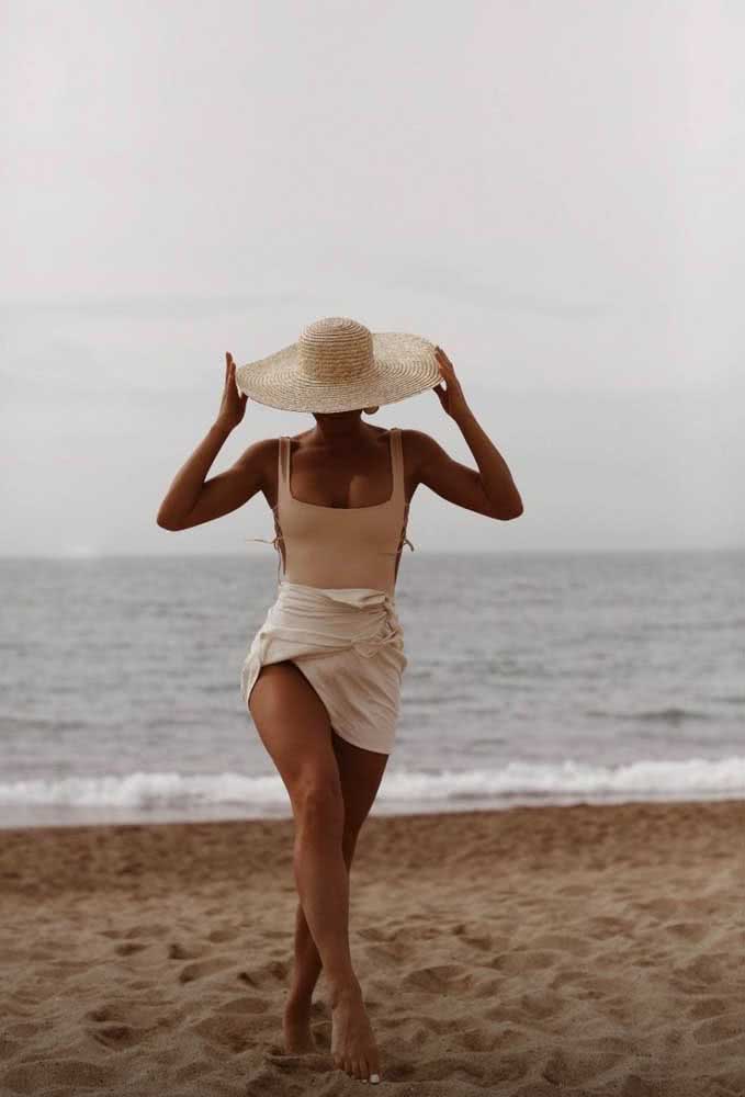 Já os tons pastéis são destaque pela leveza e elegância, como neste look praia com maiô, saia e chapéu de palha.