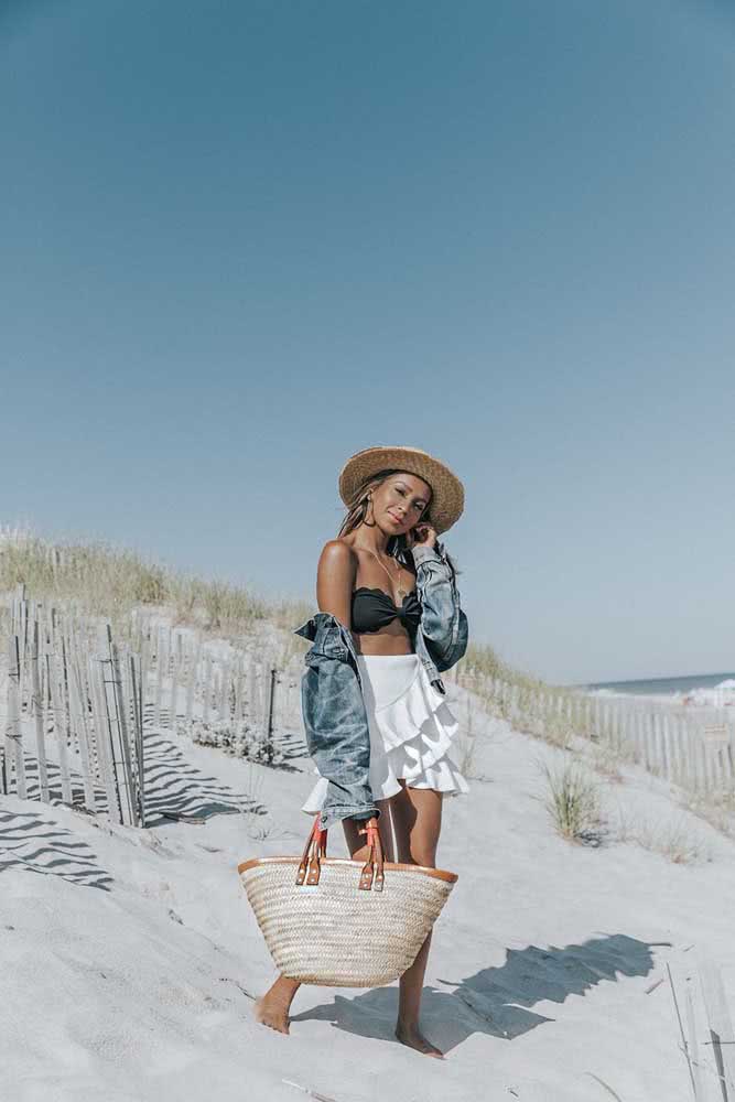 Saia com babados e uma jaqueta jeans por cima do biquíni preto fazem um look de praia perfeito para curtir um dia de sol e uma noite agitada.