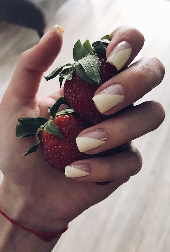 Uma composição de unhas delicadas com amarelo off-white e o tom natural da unha, separadas na diagonal.