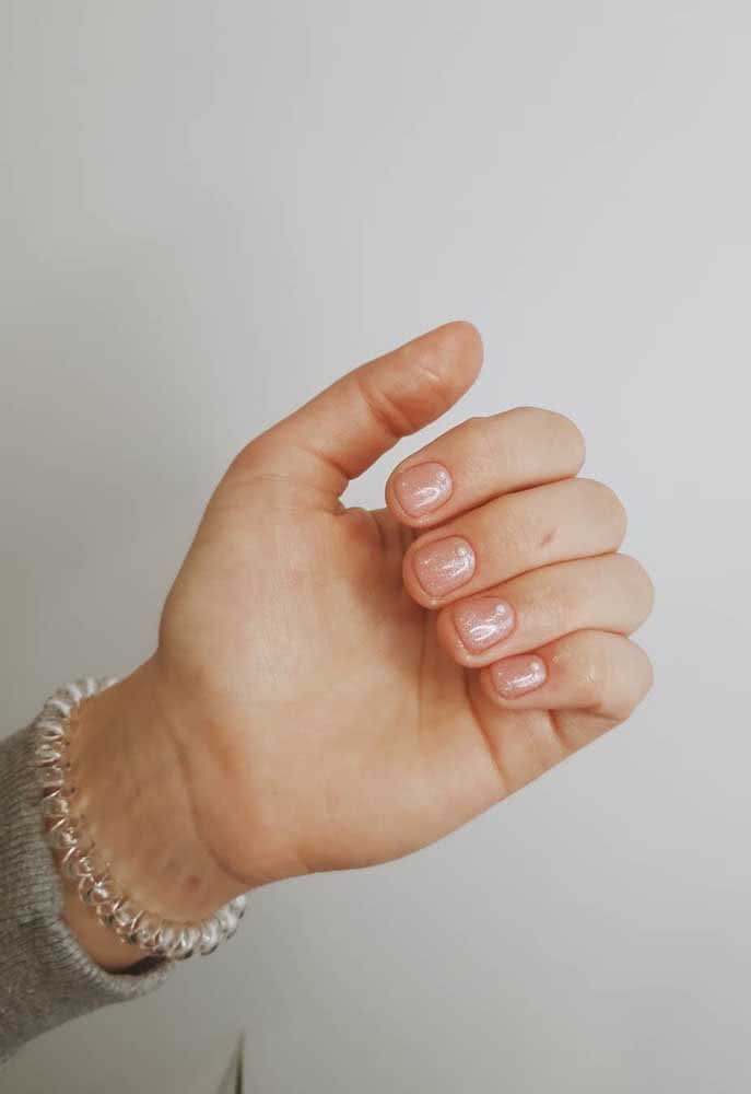 E para quem está buscando ideias de unhas delicadas curtas, aqui vai um exemplo lindo com esmalte nude com glitter. 