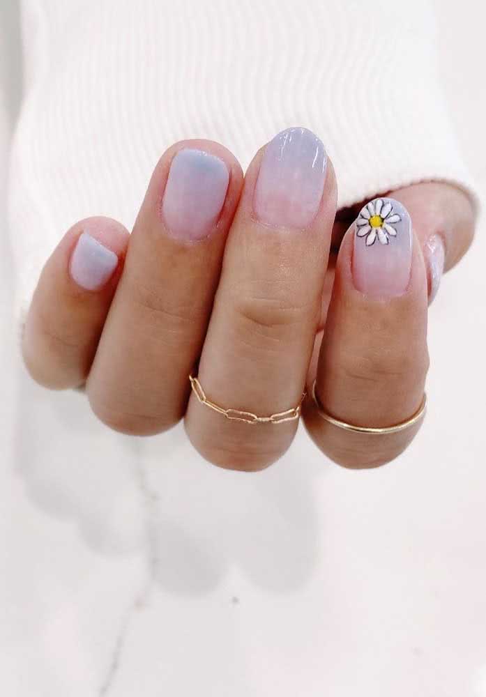 Um degradê de rosa e azul off-white combinado com a margarida na filha única é a fórmula perfeita para conseguir unhas delicadas tumblr. 