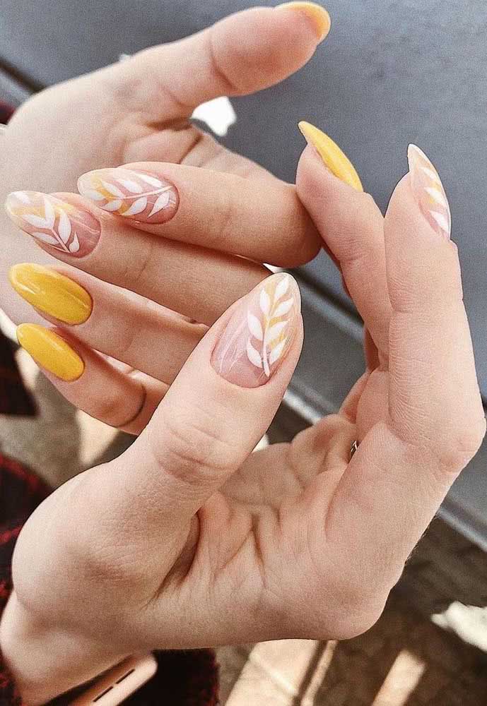 As unhas gêmeas se destacam entre as demais amarelas, com raminhos de folhas brancas sobre o fundo natural. 