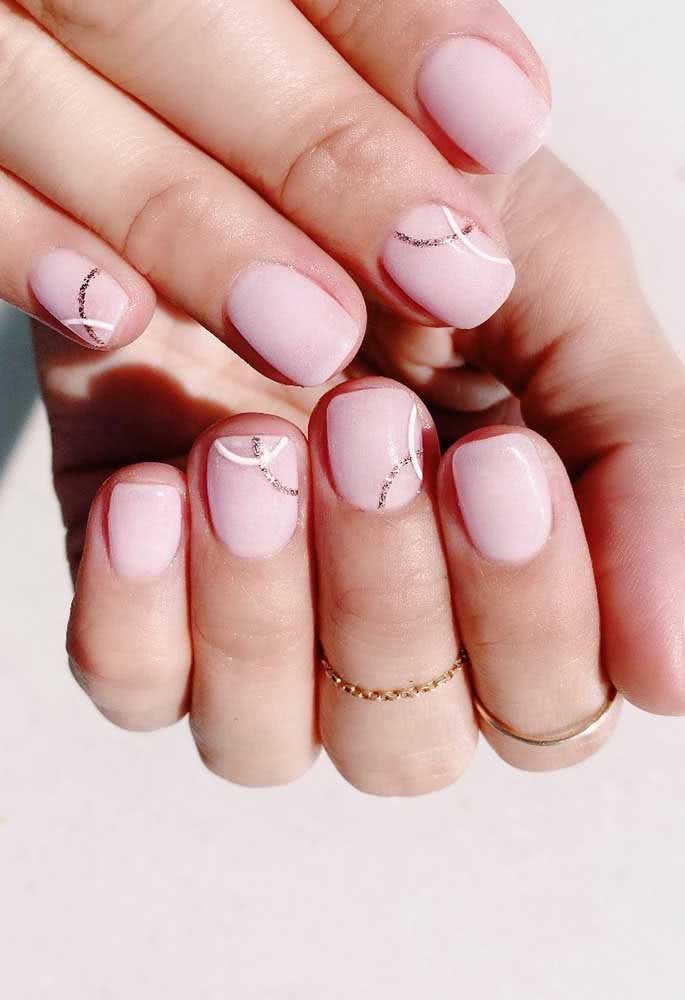 As linhas curvas brancas e cheias de brilho deixam estas unhas nude ainda mais delicadas.