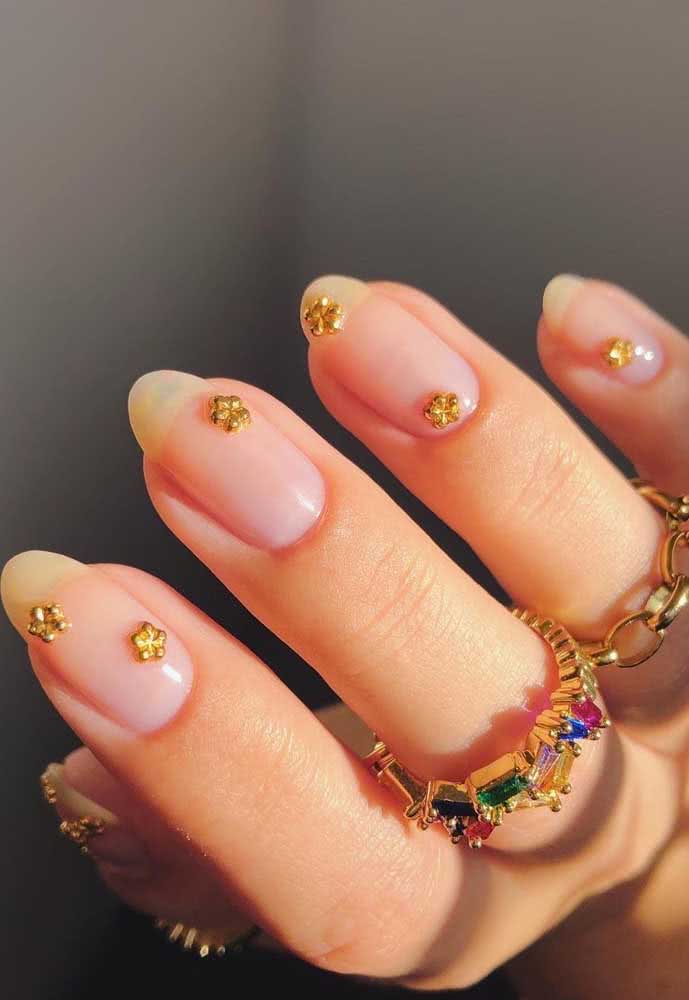 E por falar unhas delicadas com aplicação, confira estas com flores douradas sobre esmalte transparente, que valoriza o tom natural da unha. 