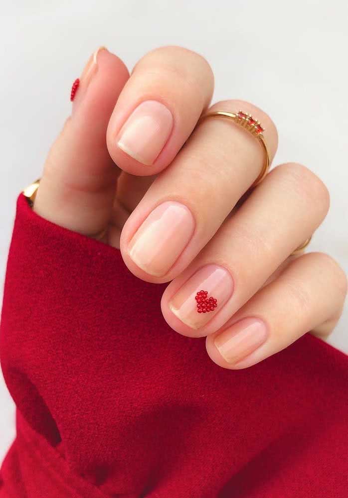 Por fim, um visual romântico e charmoso com unhas delicadas nude com aplicação de coração vermelho.