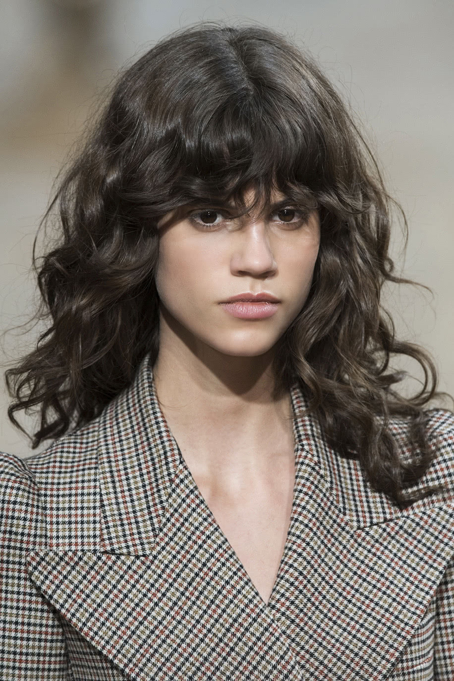 Para um look moderno e fashionista, escolha um corte de cabelo cacheado longo com franja desfiada.