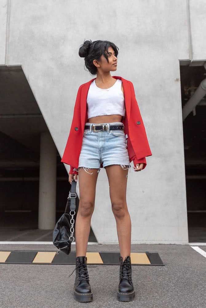 Pelo contraste que o coturno (especialmente em cor preta) gera, esse calçado é o queridinho dos adeptos ao estilo hi-lo, como neste look com shorts jeans desfiado, top branco e blazer vermelho.