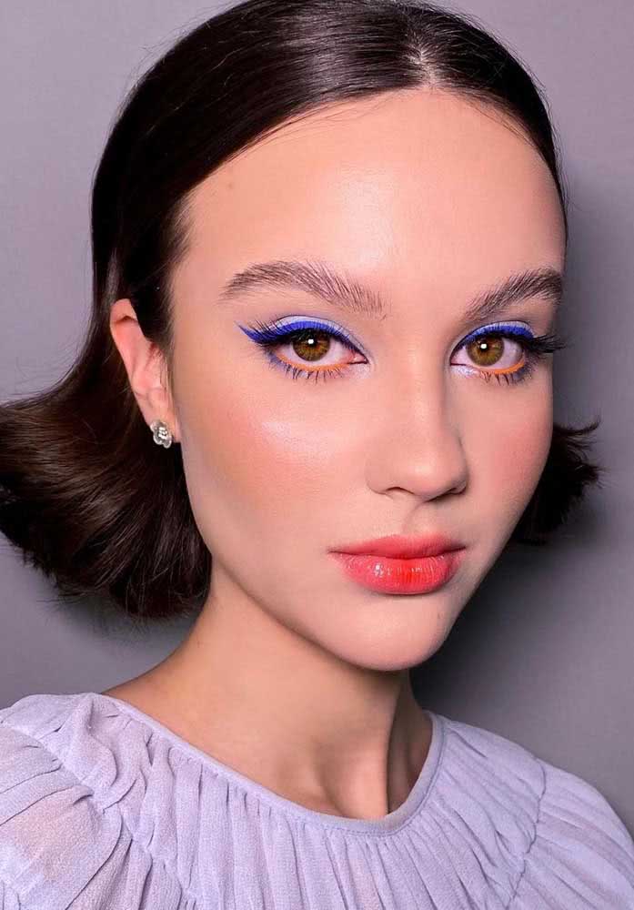 Delicada e moderna, uma maquiagem tumblr sutil com batom gloss vermelho e delineado azul nos olhos.