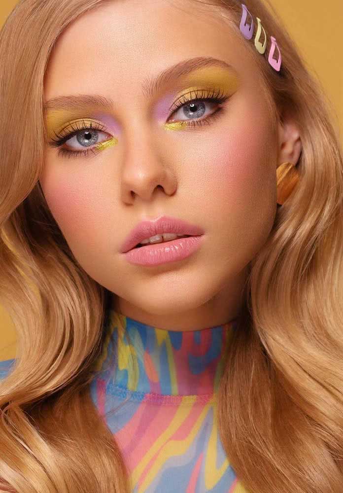 Maquiagem colorida tumblr com blush e batom rosa claro, sombra bicolor amarelo e lilás, um delineado muito sutil e cílios bem escovados.
