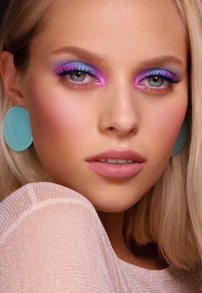 Batom e blush sutil e olhos super coloridos com uma paleta azul, rosa e roxo.