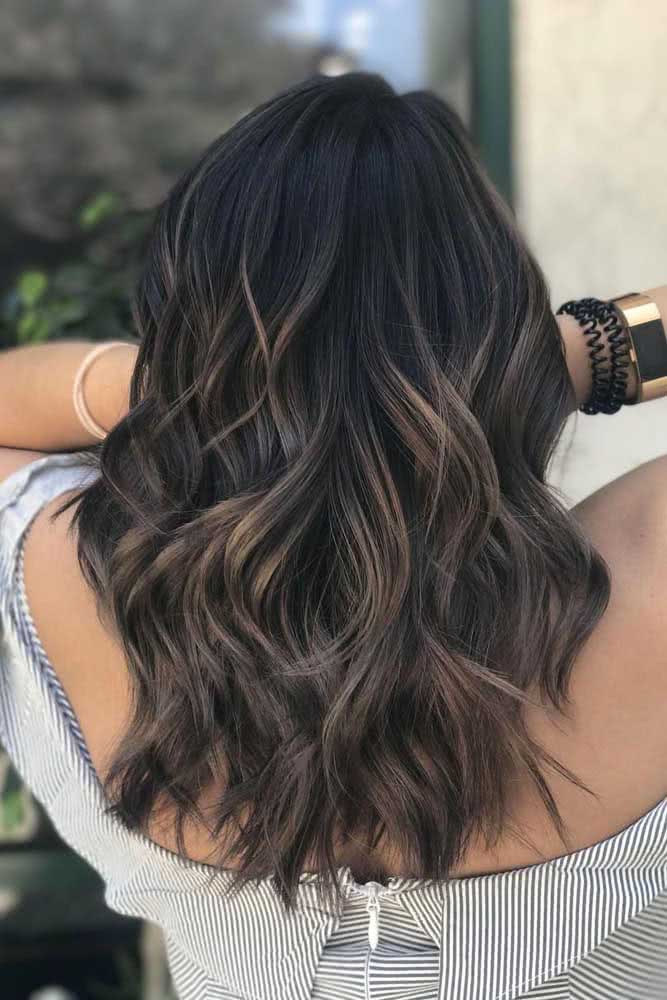 Usando a técnica balayage, este cabelo preto com luzes ouro ganha mais leveza e profundidade. 