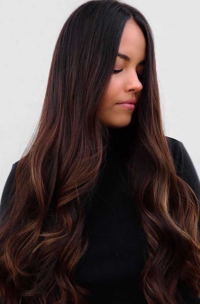 As luzes avermelhadas são suaves deixam esse cabelo preto longo mais leve e com uma iluminação natural.