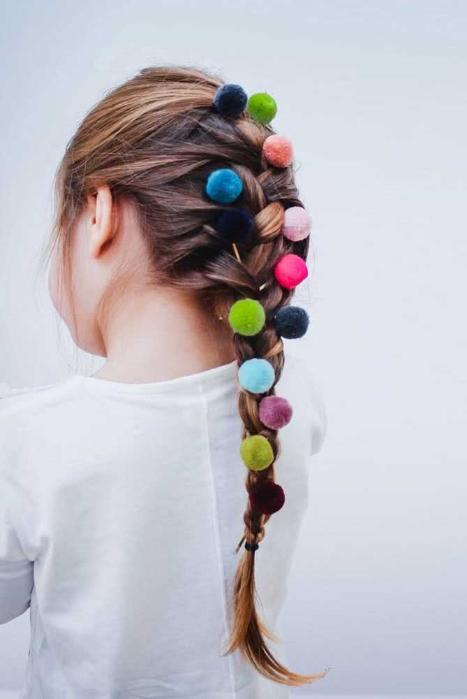Os pomponzinhos enfeitam essa trança longa, deixando esse penteado ainda mais divertido e colorido.