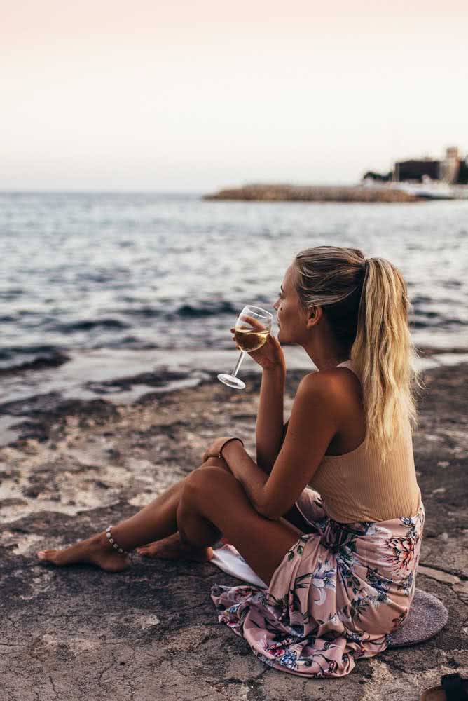 Para curtir o pôr do sol na praia e relaxar com muita praticidade, aposte em uma saída de praia pareô amarrada na cintura por cima do maiô, como neste exemplo. 