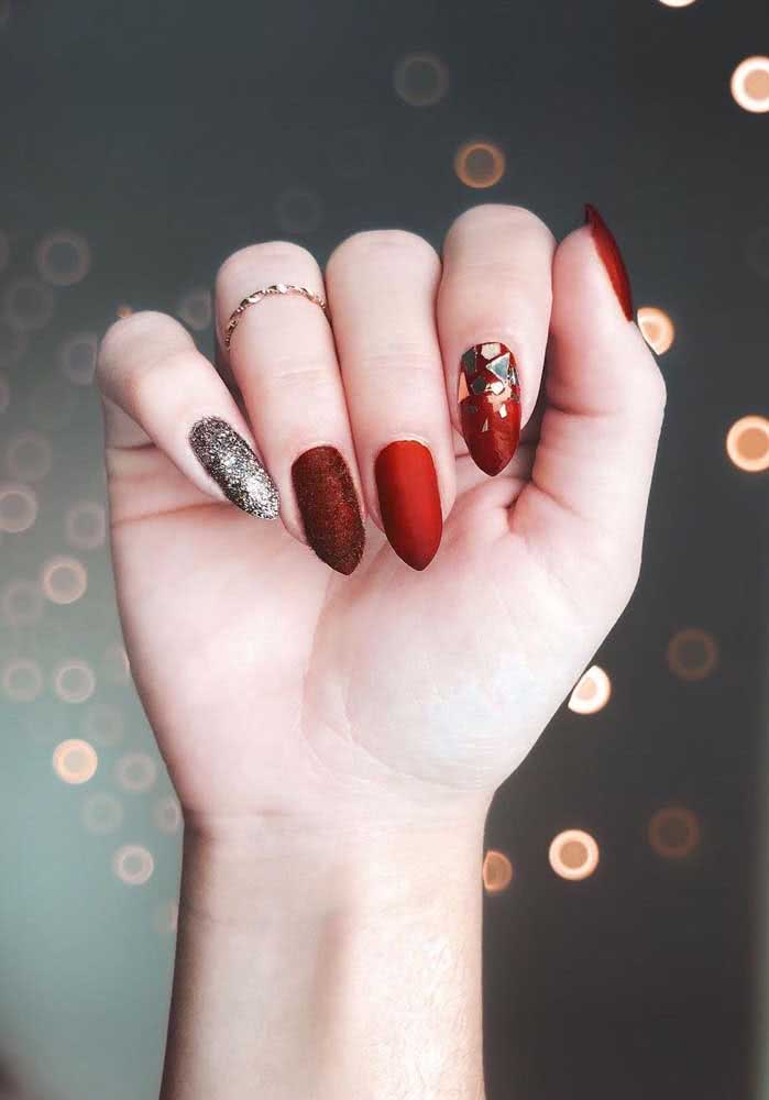 As chapinhas prateadas em formatos irregulares dão um efeito de espelho estilhaçado e trazem ainda mais atitude para estas unhas decoradas vermelhas.