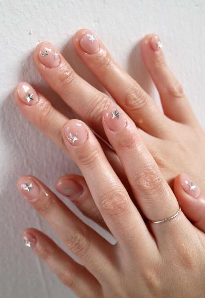 Simples e delicada, unhas curtas decoradas com pedras em formato de estrelas dispostas de forma irregular. 