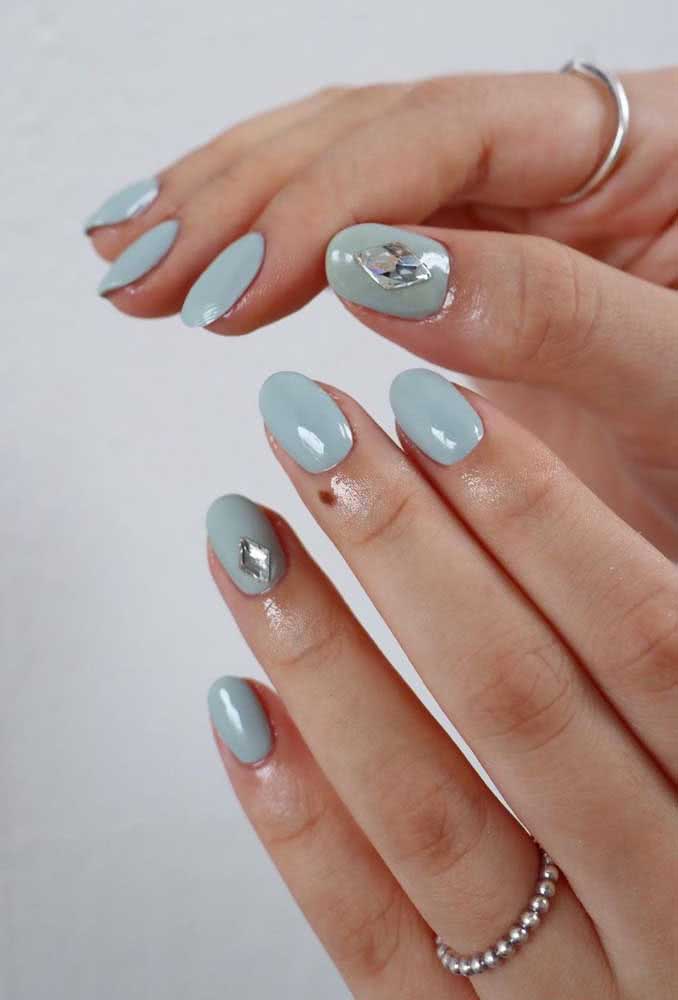 Estas unhas com esmalte azul claro ganham um toque a mais e saem da mesmice com a aplicação de uma pedra brilhante na filha única.