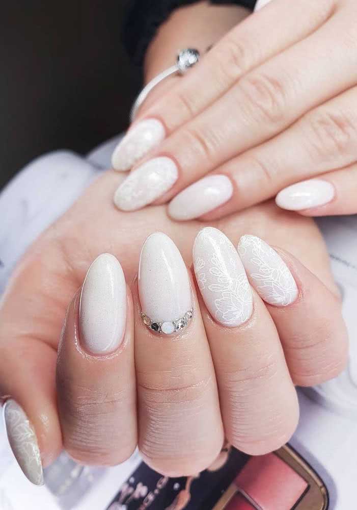 Unhas decoradas com pedras e adesivo de flores contornadas cheias de sutileza.