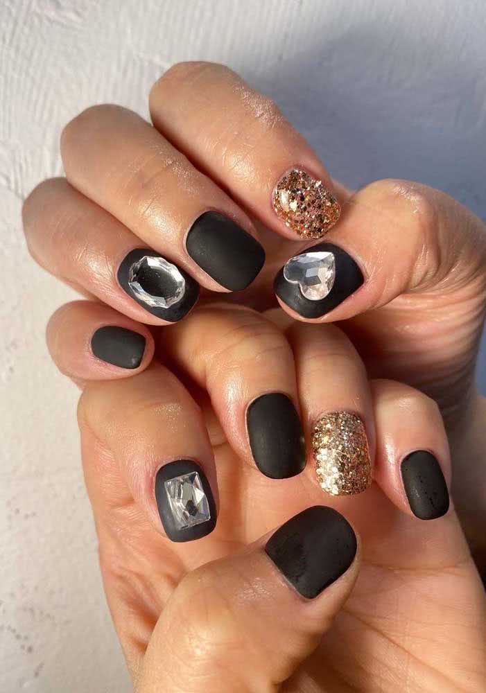 Muito brilho sobre o esmalte preto fosco com glitter e pedras transparentes.