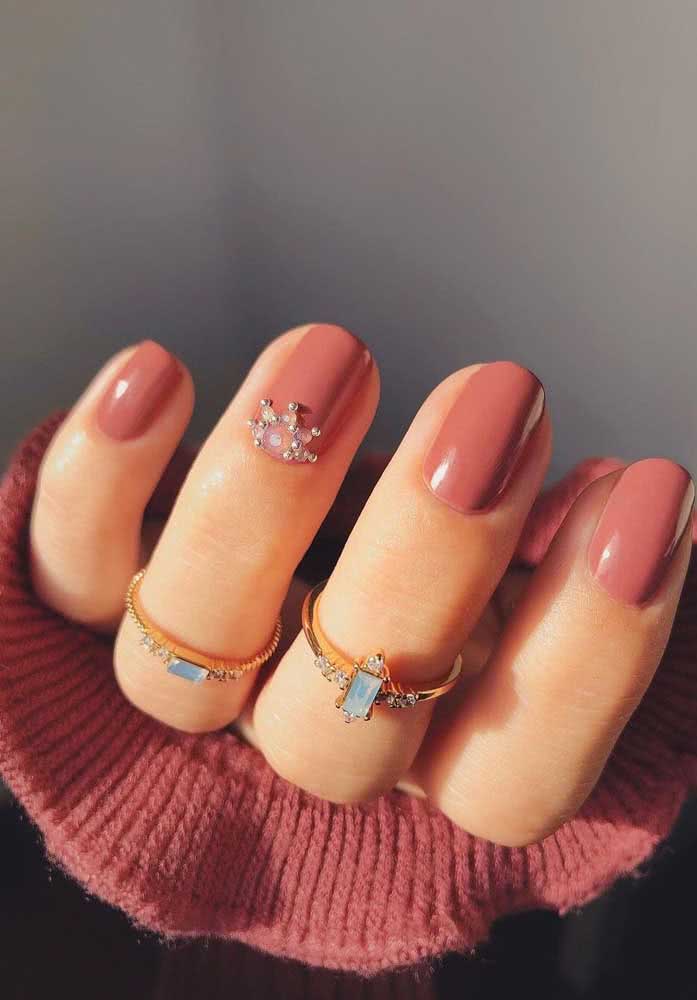 E para um visual romântico, unhas decoradas rosa com pedra em formato de sol aplicada próxima à cutícula na filha única. 