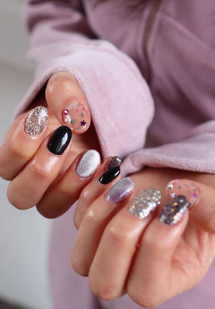 Uma das tendências do momento na nail art é usar cores e até mesmo estilos diferentes em cada unha. Neste exemplo super descontraído e divertido, além do extra-brilho e muito glitter, uma das unhas ganhou aplicação de pedras tipo chapinha redonda trazendo um efeito 3D para a composição.