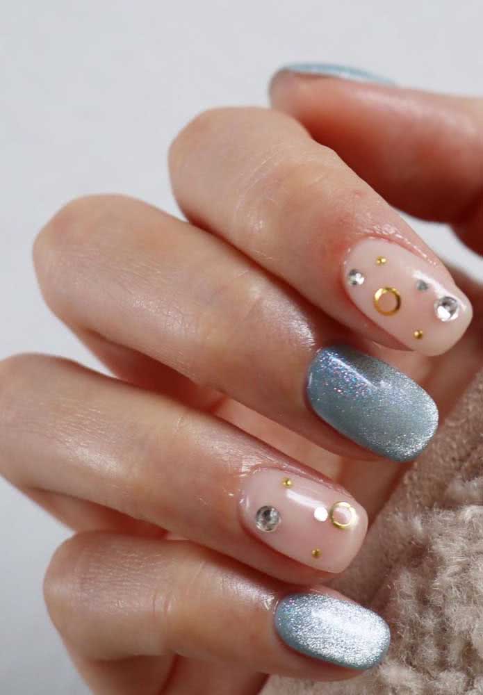 E que tal apostar num visual com dois estilos intercalados nas suas unhas? Neste aqui, um azul claro com bastante glitter compõe perfeitamente com o bege com pedrinhas douradas e prateadas.