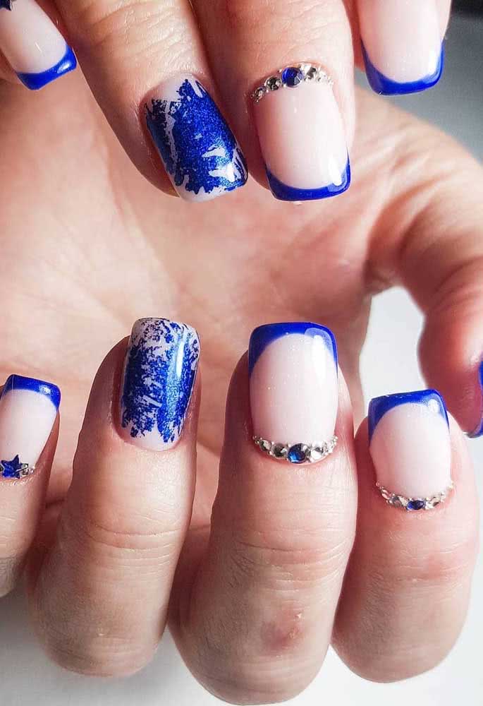 O azul anil está com tudo nestas unhas decoradas super artísticas com aplicação de pedras pequenas próximas à cutícula, fazendo oposição às francesinhas.