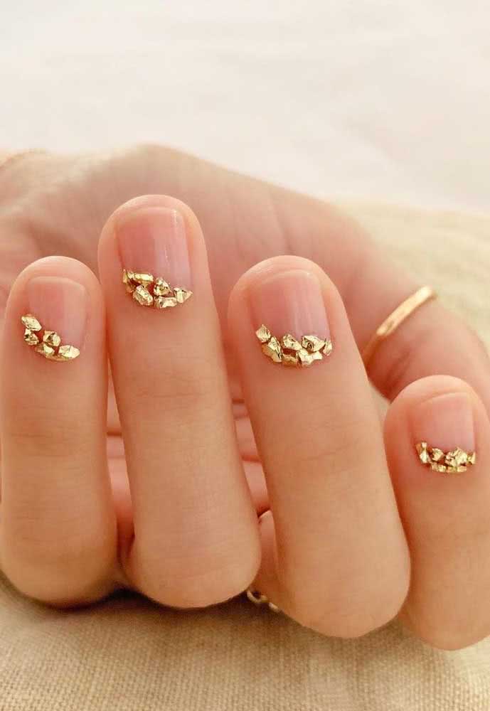 Unhas decoradas com pedras douradas aplicadas próximas à cutícula: uma ideia simples, delicada e muito sofisticada.