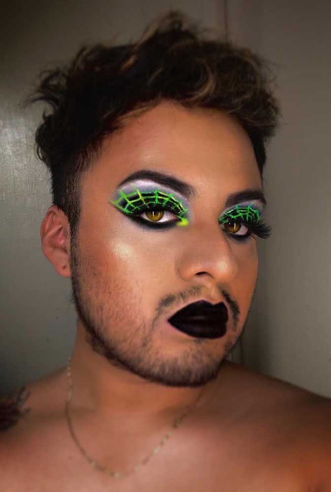 Cílios alongados e teias de aranha em preto e verde neon nos olhos e batom preto nos lábios formam uma maquiagem de halloween simples, criativa e com um toque glam. 