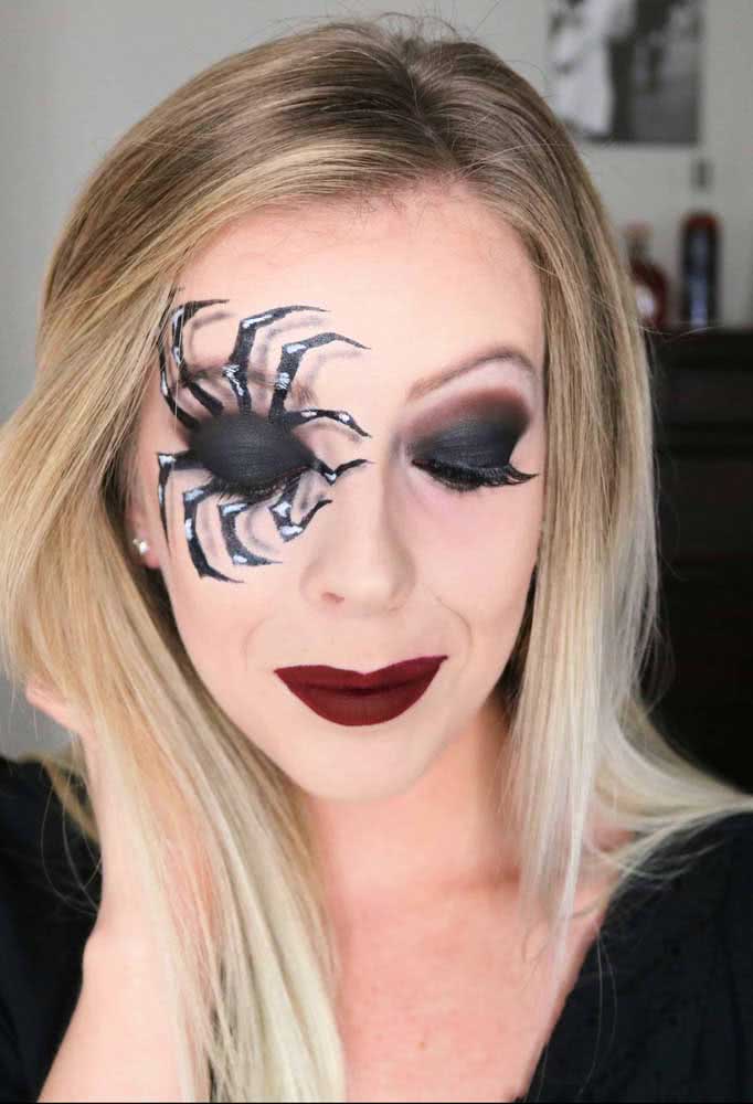 Aposte em uma sombra preta bem poderosa para formar o corpo de uma aranha e arrase no desenho das pernas com alguns detalhes em branco nesta ideia de maquiagem de halloween super criativa.