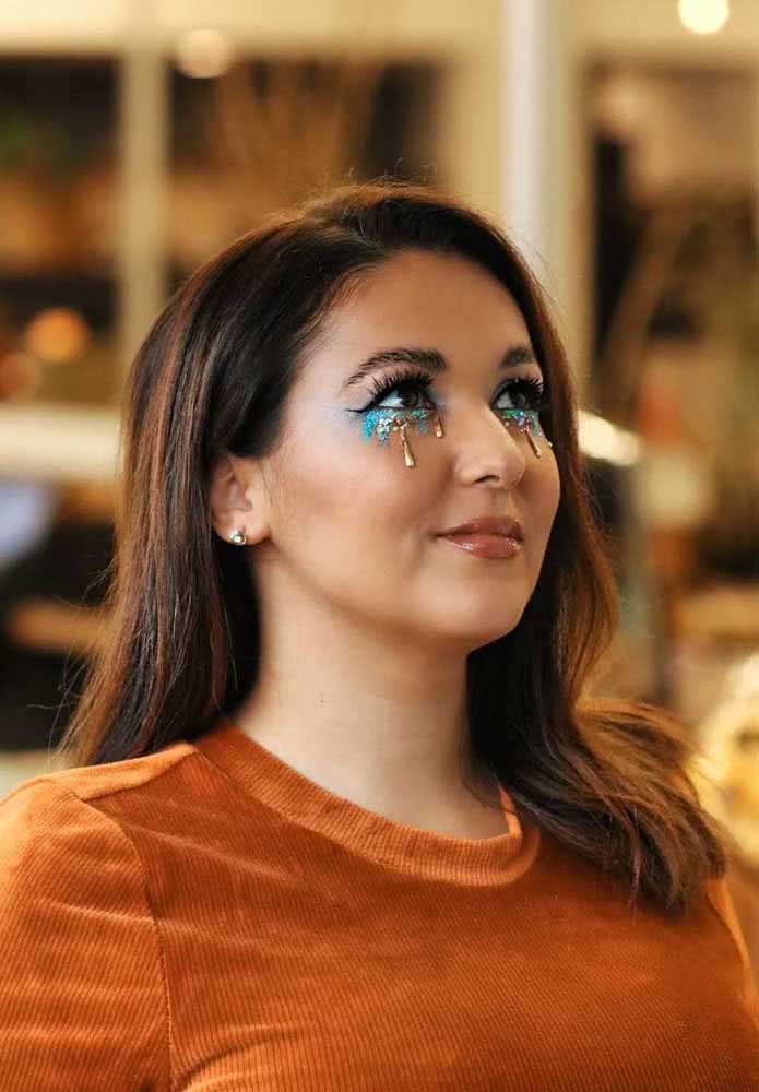 Uma ideia simples mas cheia de criatividade, magia e glamour para curtir o halloween: sombra glitter azul turquesa abaixo dos olhos e lágrimas douradas escorrendo. 