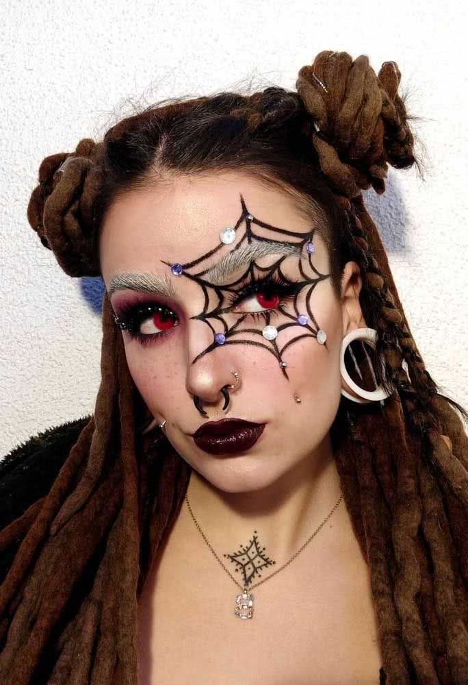 Traços precisos com lápis preto para criar uma teia de aranha ao redor do olho nesta maquiagem de halloween sombria. 