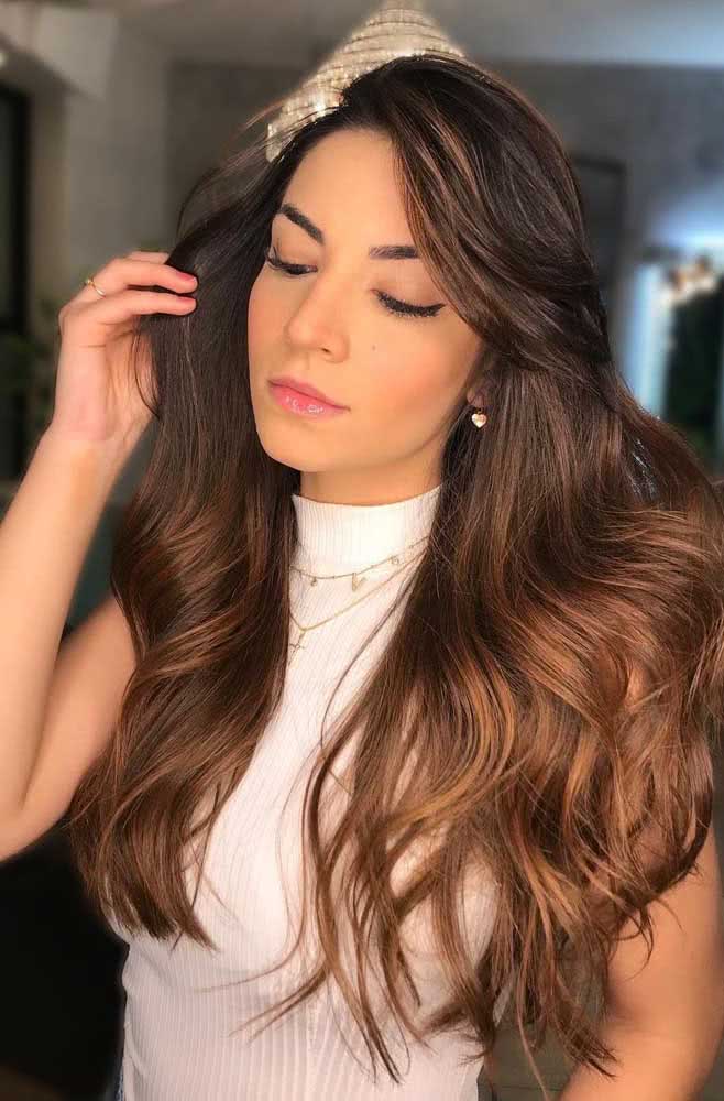 O visual morena iluminada mel é uma ótima forma de deixar o volume do cabelo mais leve, especialmente se você gosta de usá-lo repartido de lado.