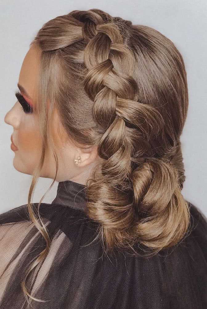 Experimente fazer um penteado preso lateral, com uma trança holandesa que cai e se transforma num coque próximo à nuca. 