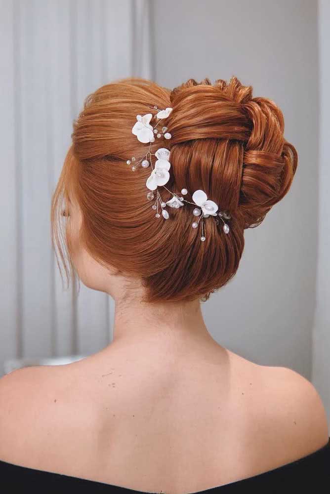 Outra ideia de penteado preso super elegante para casamentos e eventos formais é este coque nó alto com adorno de flores delicadas e topetes.