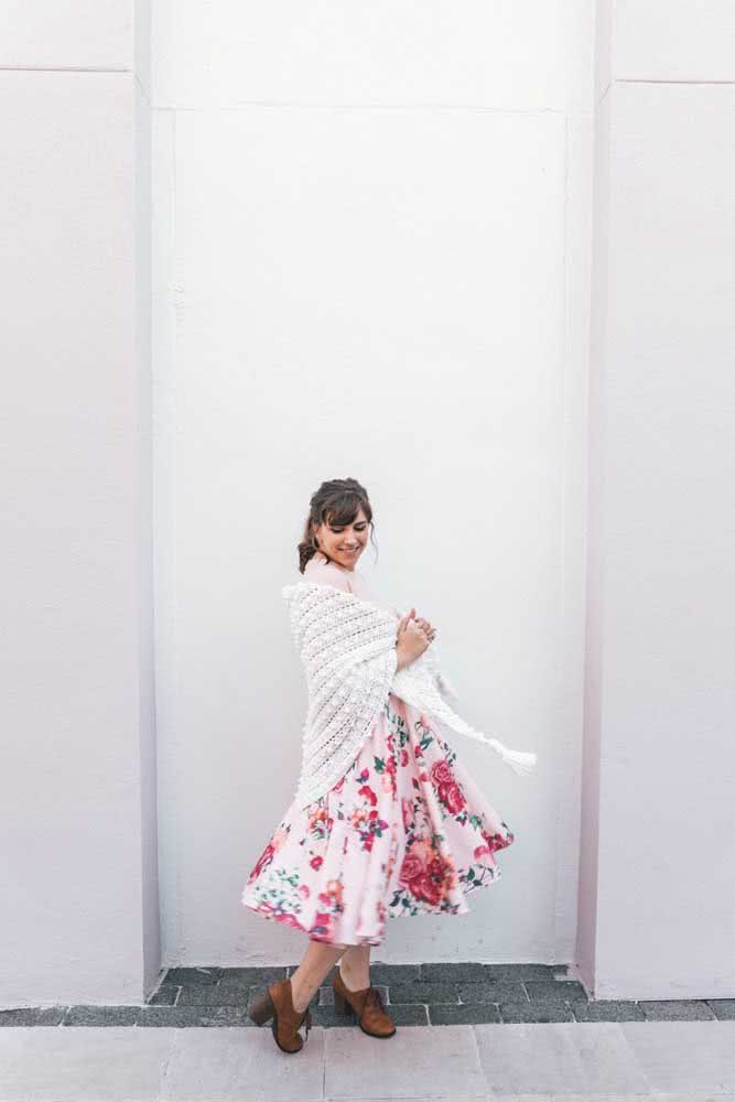 Look cheio de movimento e estilo com xale de crochê branco triangular sobre vestido rodado floral e oxford caramelo com salto.