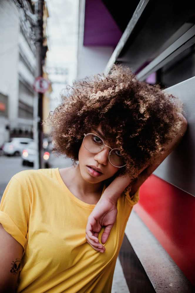 Um visual cheio de profundidade com mechas de vários tons diferentes neste cabelo crespo médio com franja. 