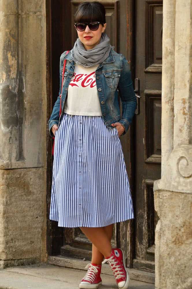 Look com tênis vermelho all star de cano alto com saia midi listrada, camiseta, jaqueta jeans e lenço para curtir o dia. 