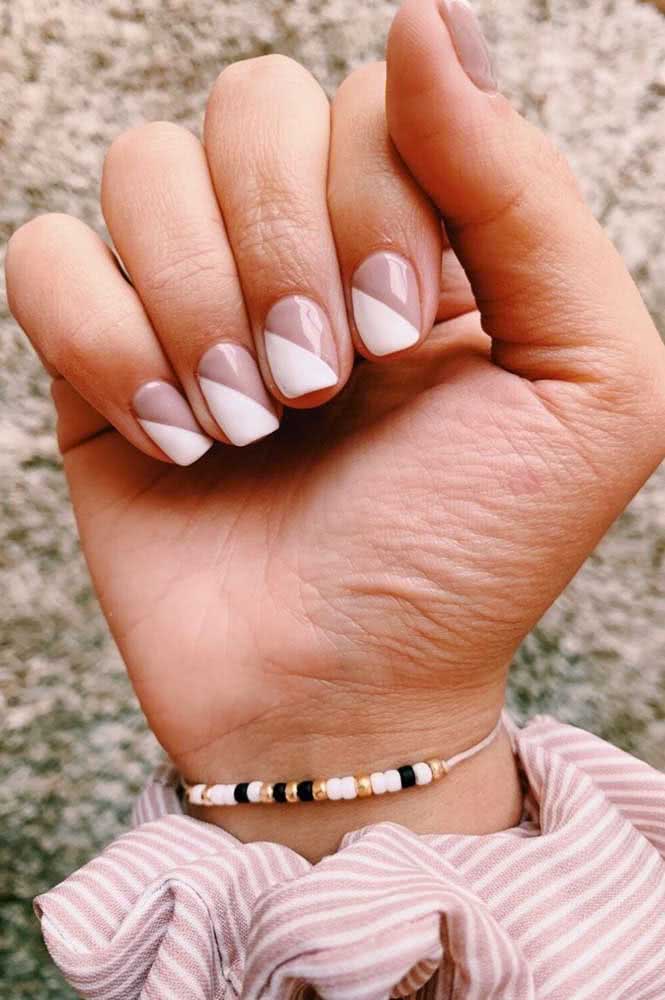 Unhas meio a meio, também conhecidas como half nails, divididas na diagonal em branco e nude fazem um visual moderno e elegante. 